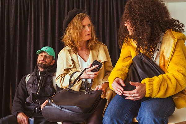 deux fille sont assise et discute tandis qu'un garçons est assis derrière elle.