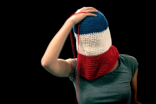 Une femme a la tête caché par de la laine qui l'entoure représentant le drapeau de la France.